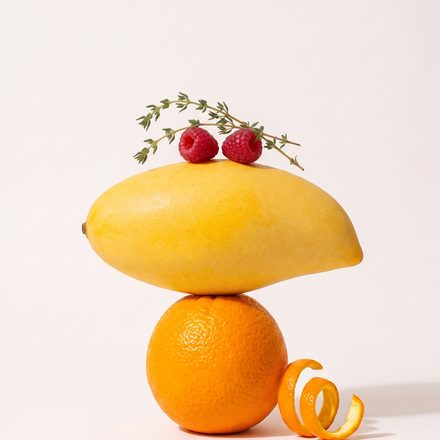 Lemon and orange balanced in a stack against white