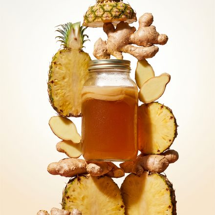 Pineapple and ginger stacked around a jar of amber ferment