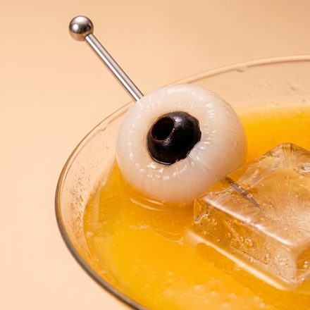 Lychee skewer across a glass of golden ferment