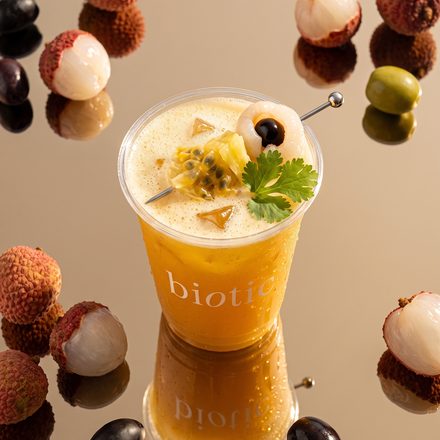 Biotic cup surrounded by floating lychees and olives