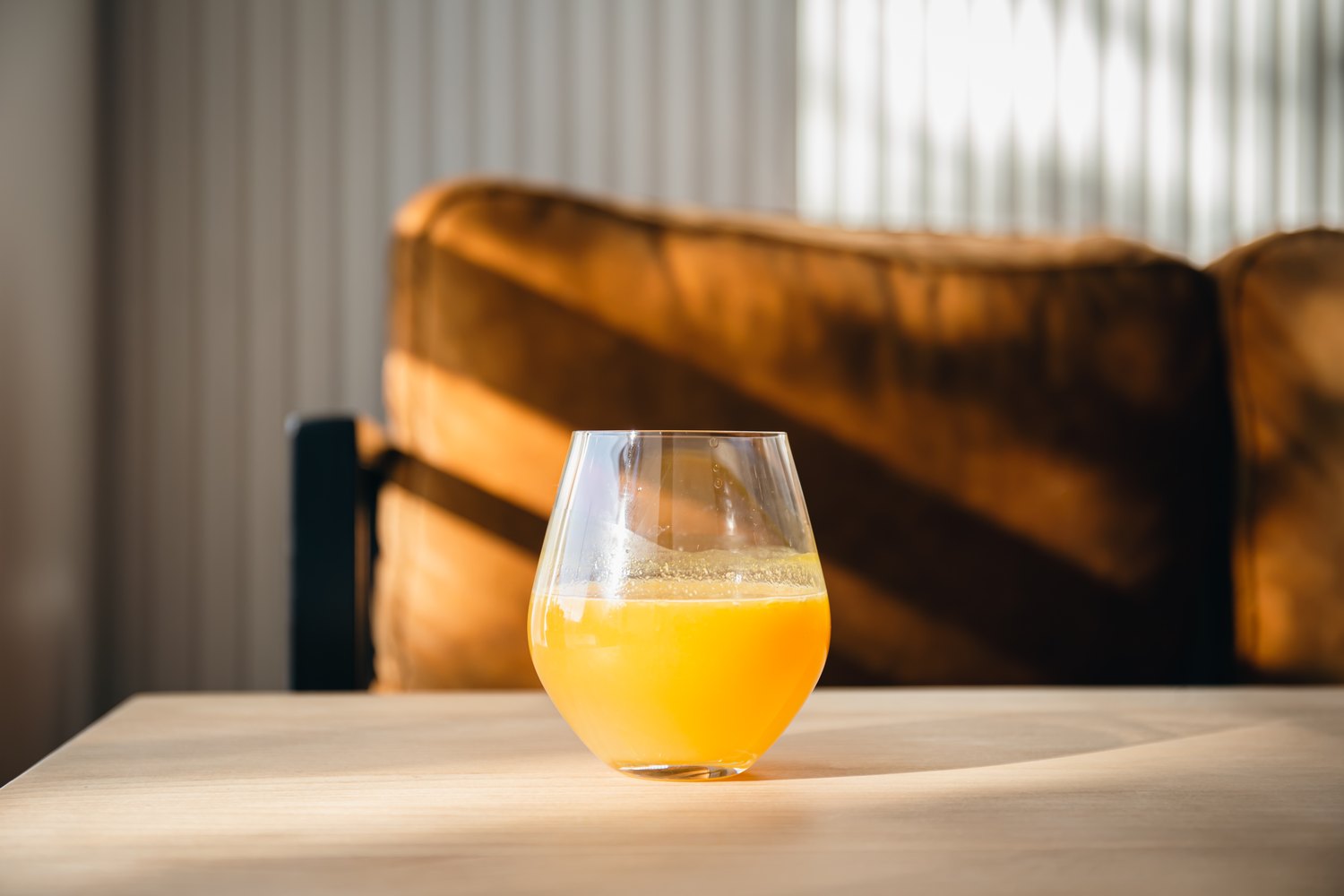 A glass of fresh juice on a table in morning light