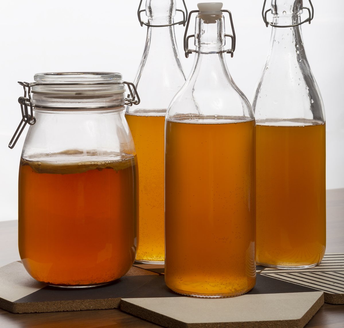 A jar of kombucha beside swing-top bottles of finished ferment