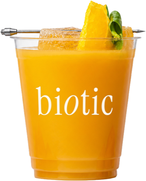 Golden carrot, mango and orange drink in a plastic cup with fresh basil