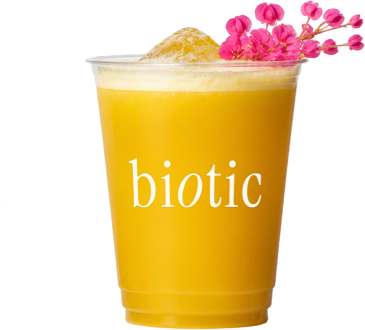Golden pineapple and passion fruit drink in a plastic cup with pink blossoms
