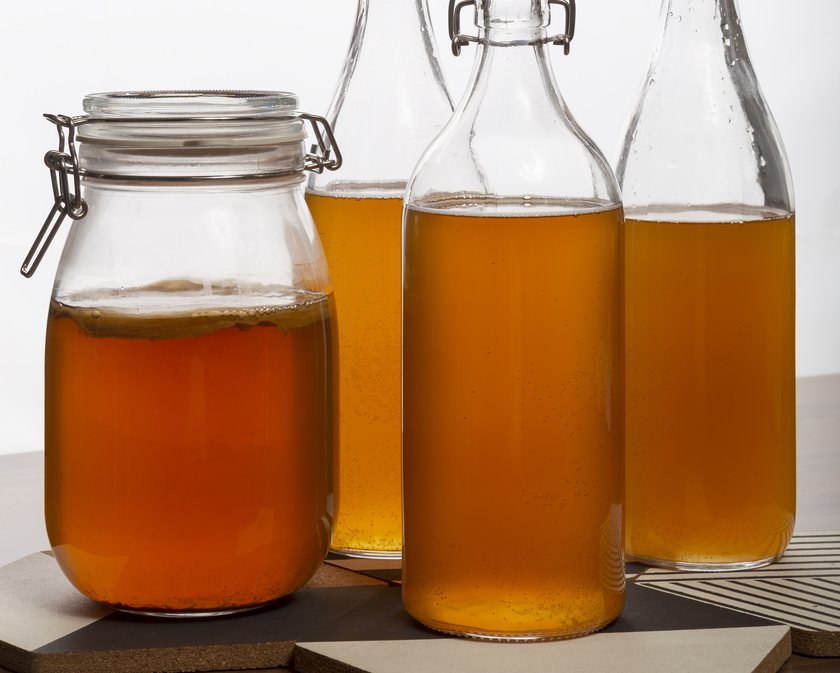 A jar of kombucha beside swing-top bottles of finished ferment