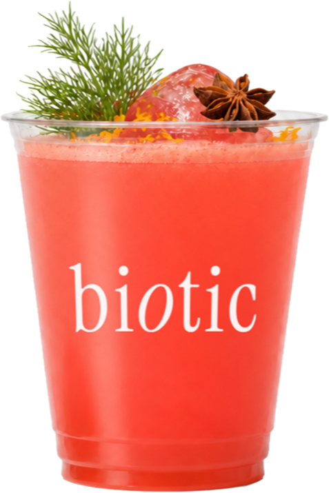 Deep red roselle drink in a ridged plastic cup with dill, star anise and orange zest