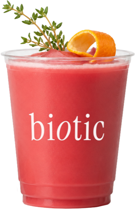 Red strawberry drink in a plastic cup with fresh strawberries, basil and an orange twist